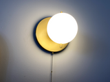 brushed brass round wall lamp with round frosted glass shade. Light turned on